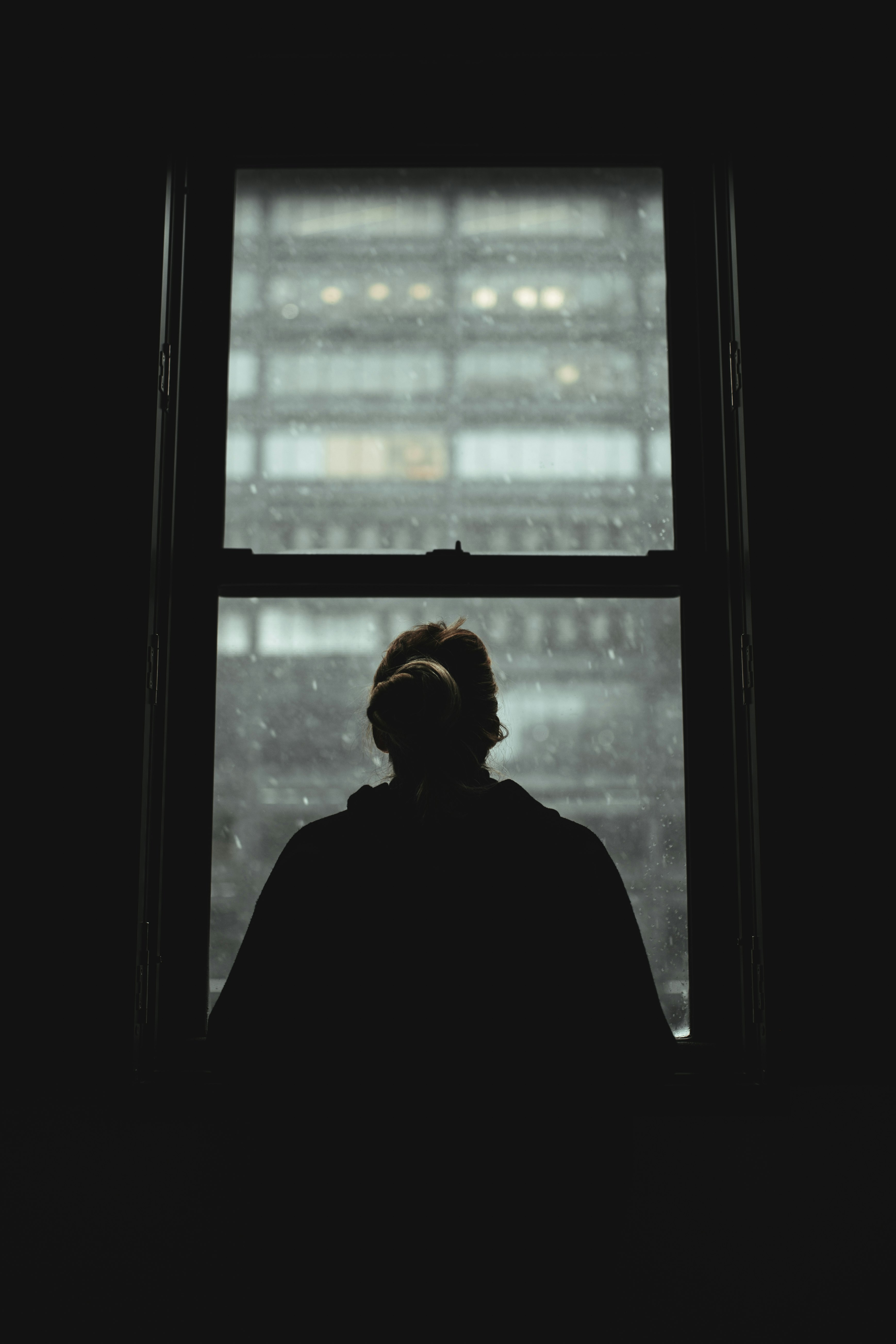 man in black jacket standing near window